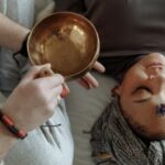 Woman receiving healing therapy with a Tibetan singing bowl placed during meditation.